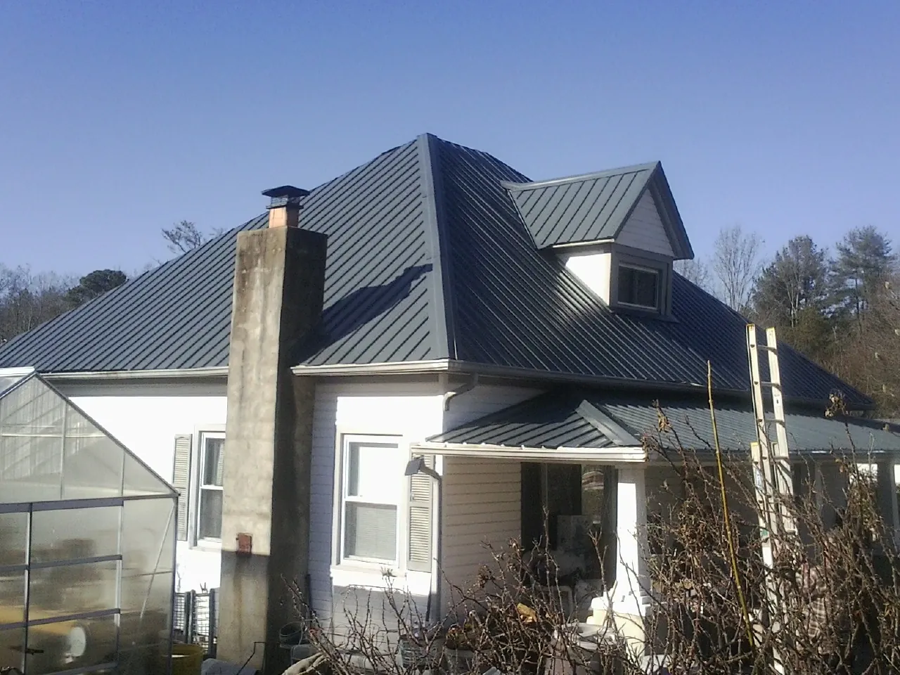 Dark blue standing seam metal roof on a white farmhouse with dormer — Slate & Tile Roof Repair by Roofing Brothers in Tulsa