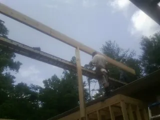 Carpenter setting a ridge beam over a new addition frame — Ice Dam Removal by Roofing Brothers in Tulsa