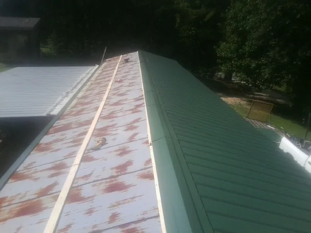 Old rusted panels beside newly installed green metal roofing — Wind Damage Roof Repair by Roofing Brothers in Tulsa