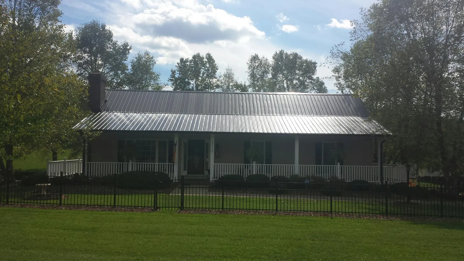 Gray metal roof on a brick ranch with a full width front porch — Gutter Guard Installation work by our crew in Tulsa